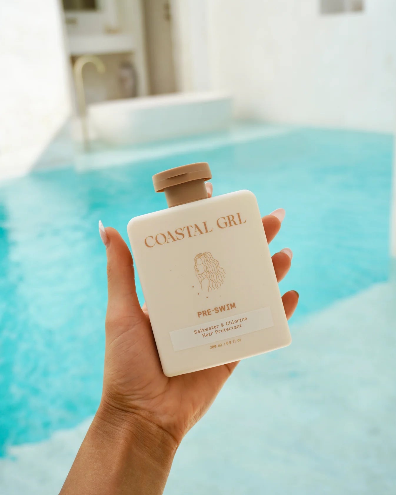 Hand holding a 'Coastal Girl' product by a pool