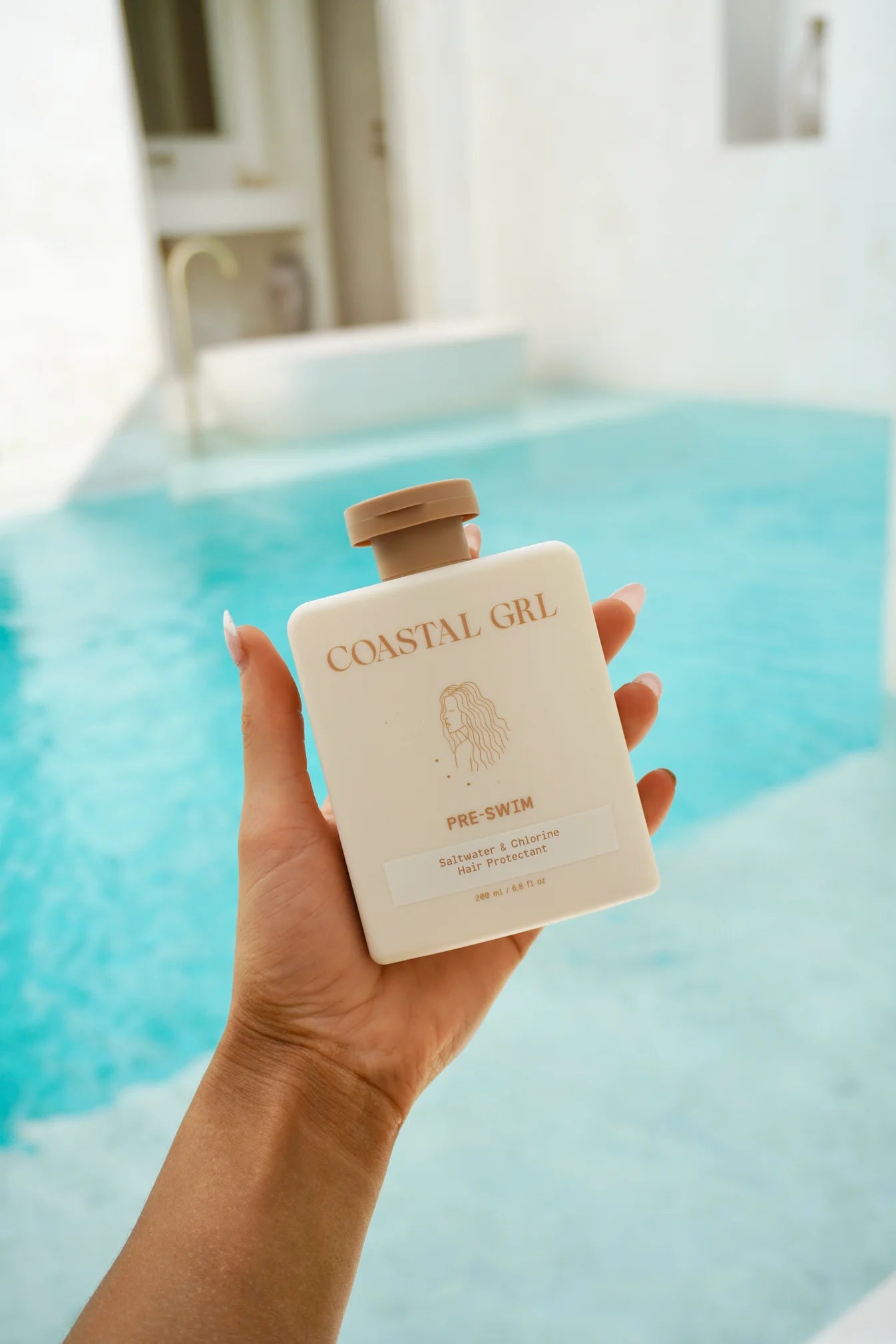 Hand holding a 'Coastal Girl' product by a pool