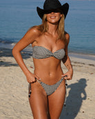 Woman in a checkered bikini and cowboy hat on a beach